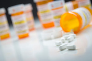 Variety of Medicine Bottles Behind Pills Spilling From Fallen Bottle.