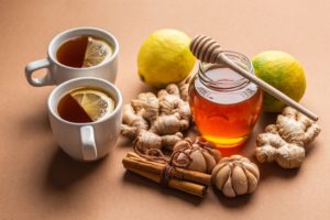Natural cold and flu home remedies: hot tea cups with lemon, honey, ginger, cinnamon and garlic to boost immune system. Natural healthy food ingredients for immunity stimulation, viruses protection